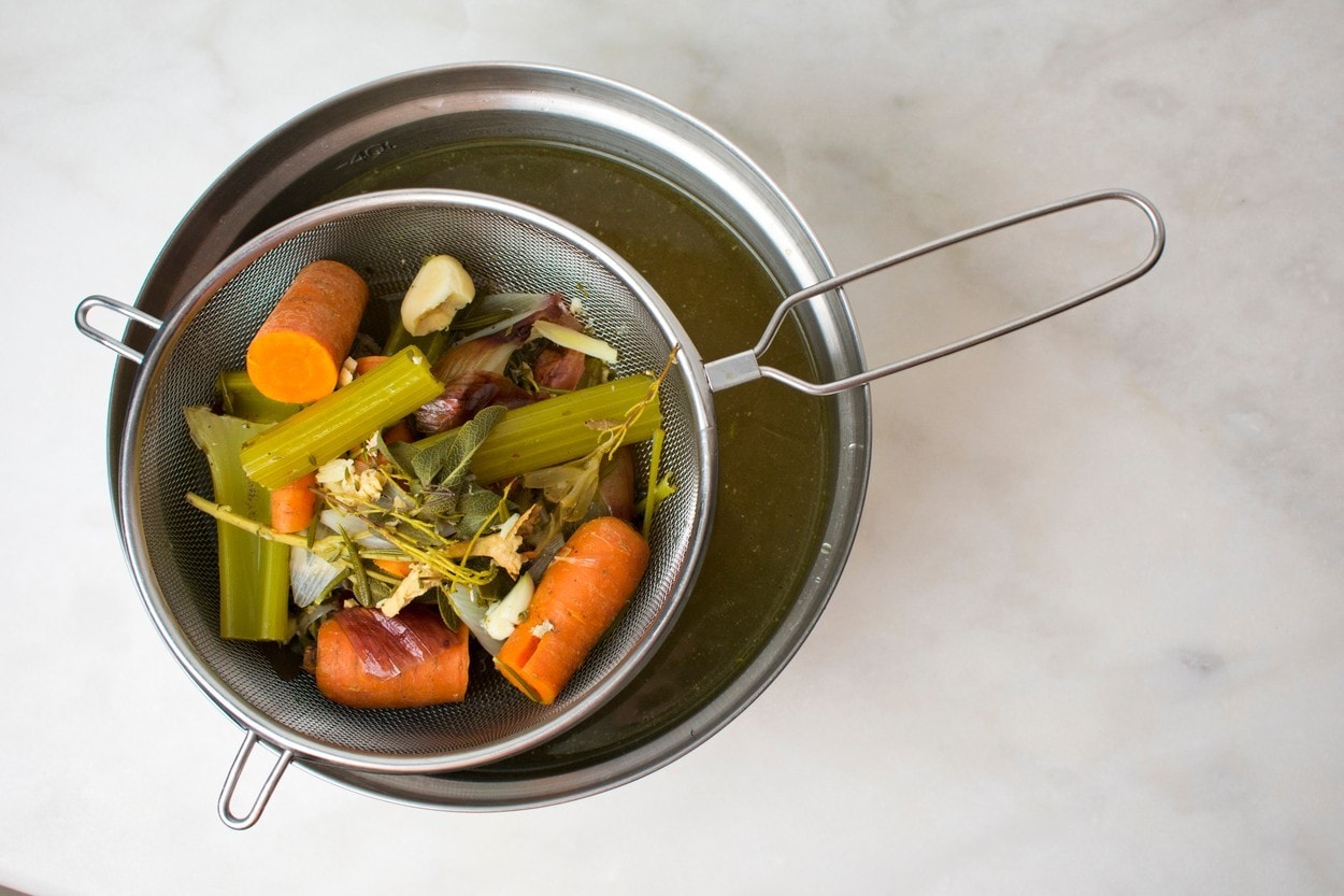 Straining the herbs and vegetables while making broth