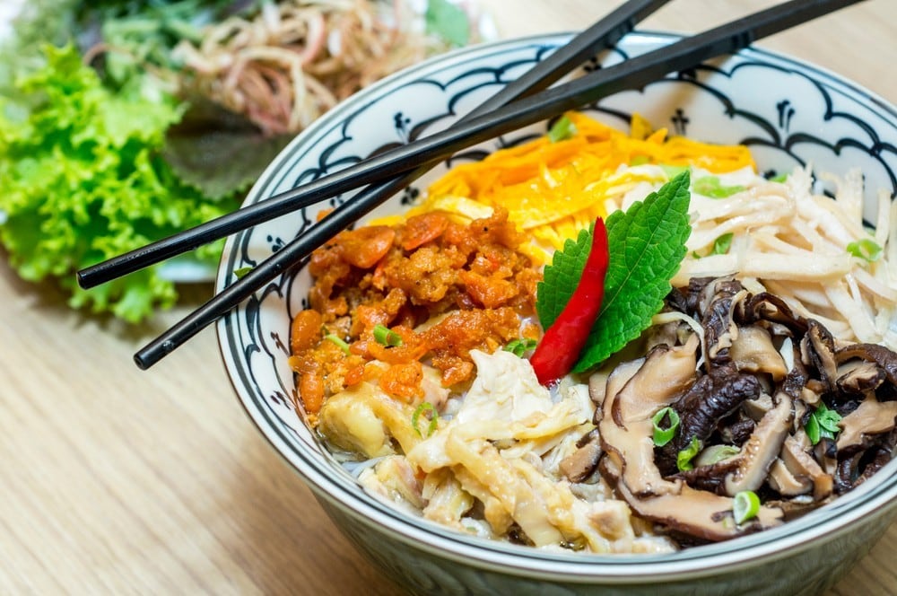Bun Thang - traditional vietnamese rice noodle soup with shredded chicken, ham and eggs, shrimp, mushroom which is garnished by chopped cilantro, spring onion and chili slices.