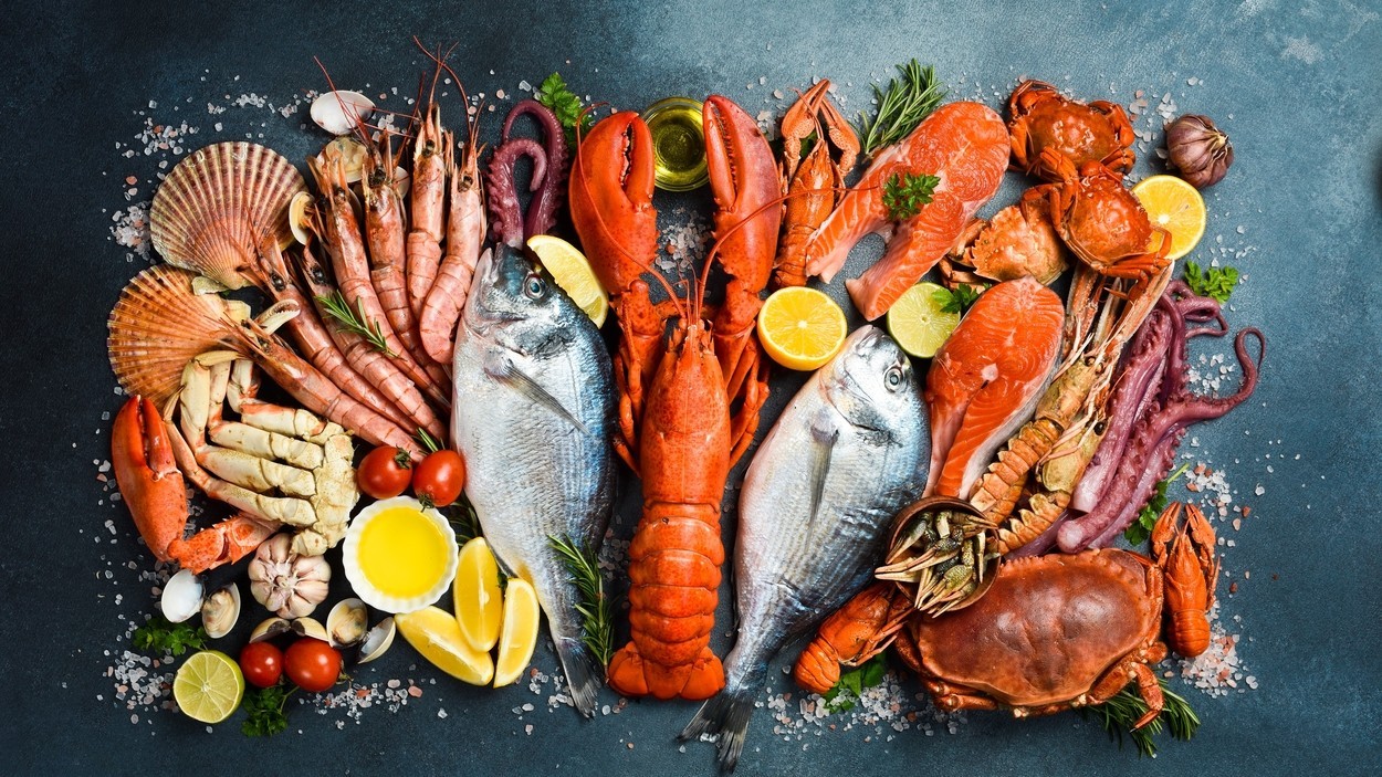 Fresh Seafood Background. Assortment of seafood: Fresh fish, shrimp, oysters, lobster and octopus on slate black table. Top view.