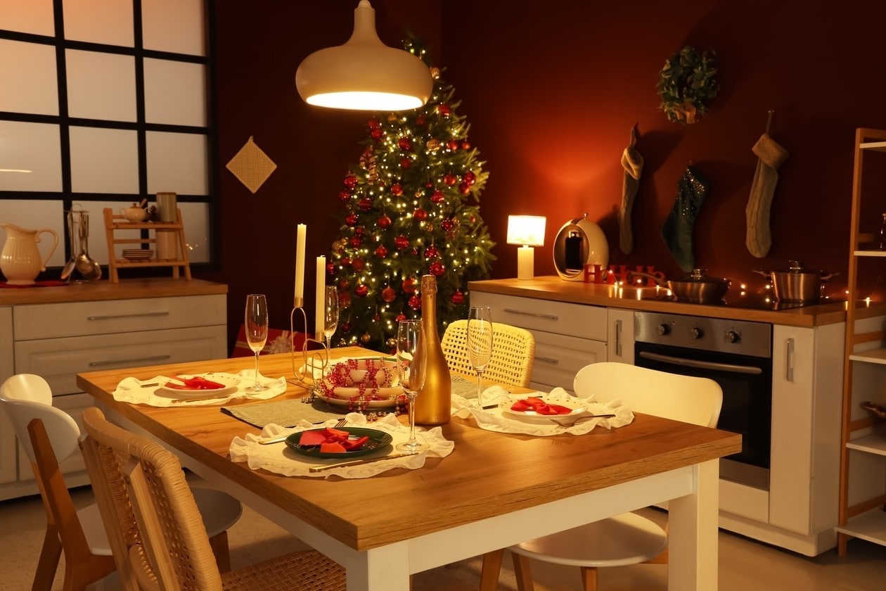 Interior of dark kitchen with glowing Christmas tree, counters and dining table