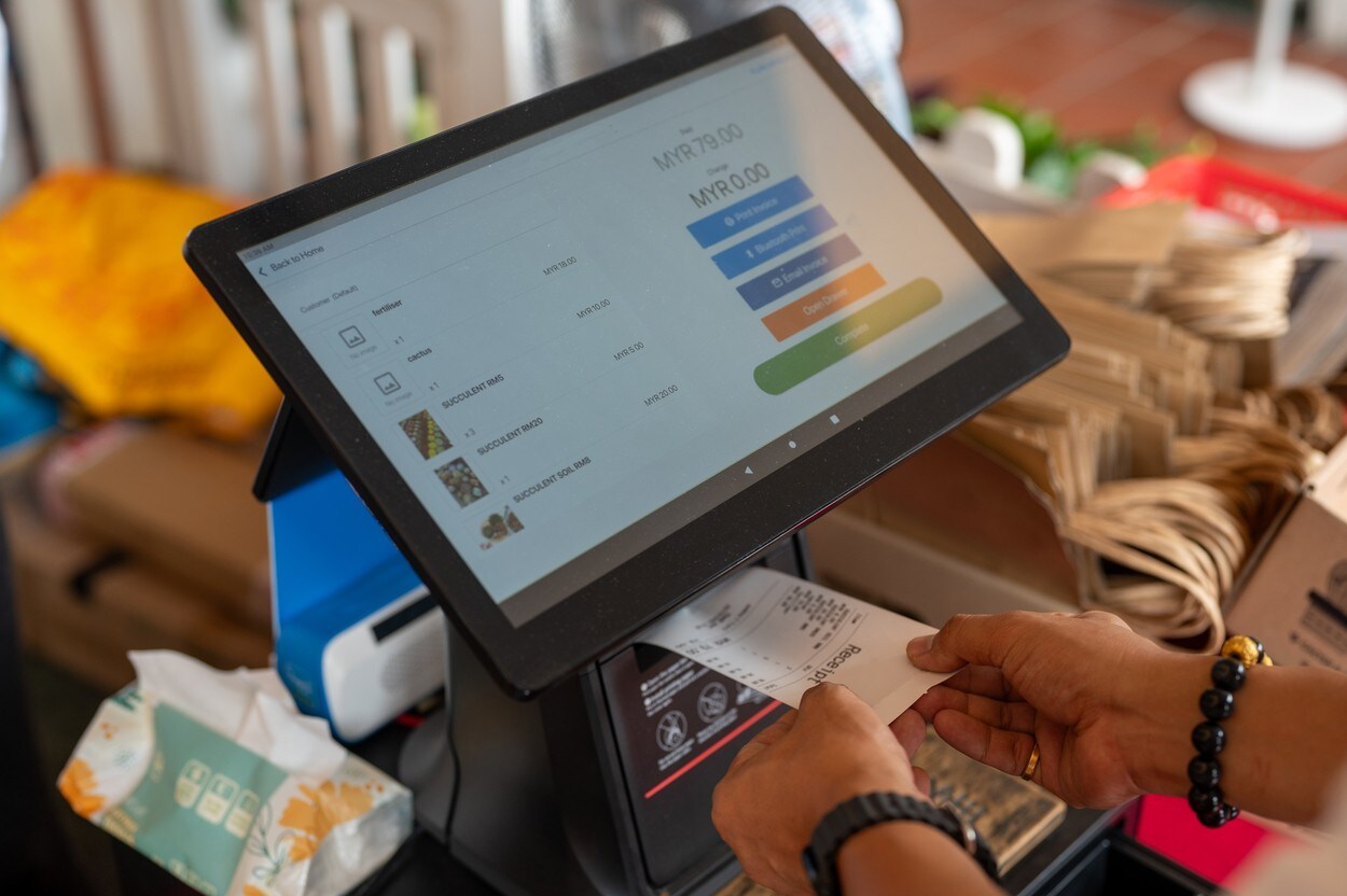 Picture of cashier is printing receipt with cash register machine in pottery and flowers shop. After Salesman receiving payment from customer in store.