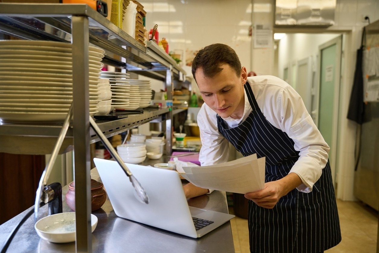 Cook is working with documents at the kitchen rack