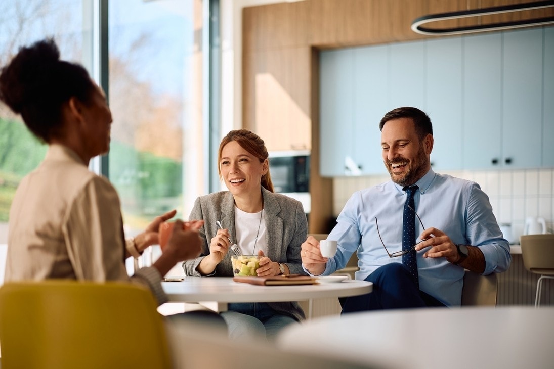 Group of happy business colleagues communicating at office cafeteria.