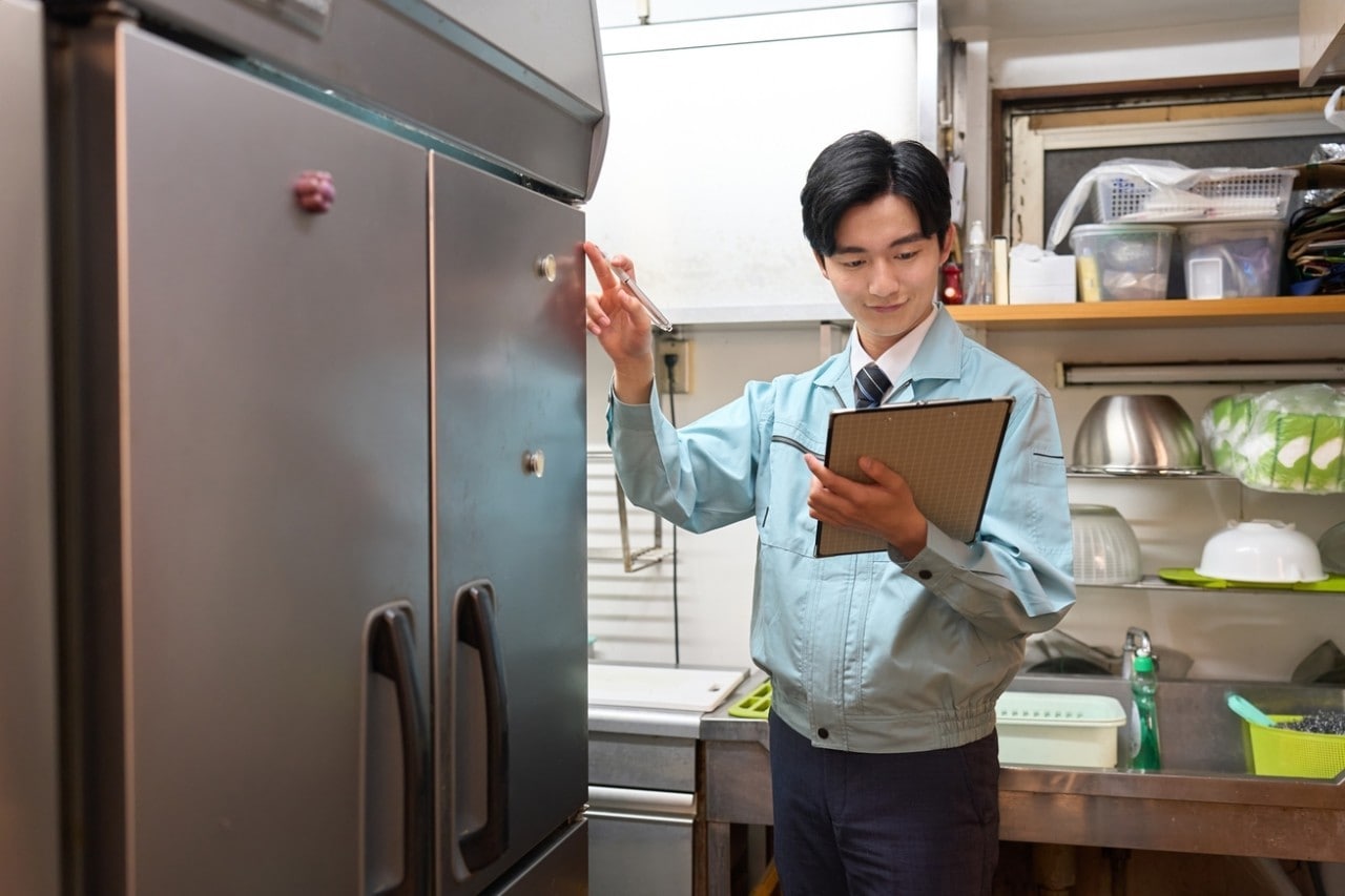 A man checking a restaurant's refrigerator