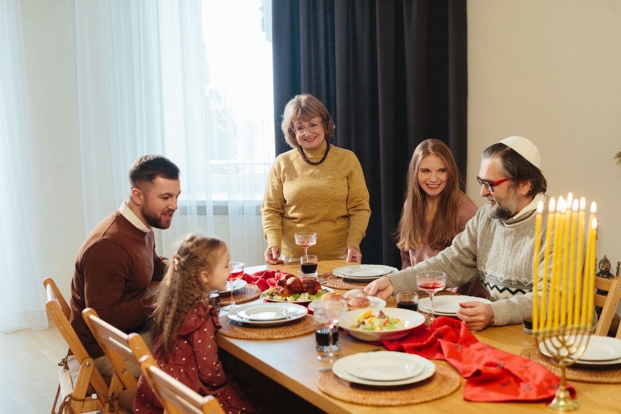 Multi-generational jewish family gathering around dining table, enjoying traditional food and celebrating hanukkah