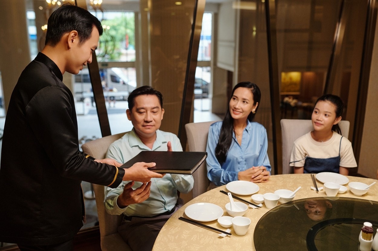 Waiter Giving Menu To Family In The Restaurant