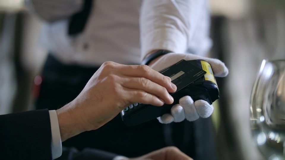 Male hands paying by credit card at terminal at restaurant. Close up man using bank card for paying restaurant bill. Closeup of credit card payment in cafe